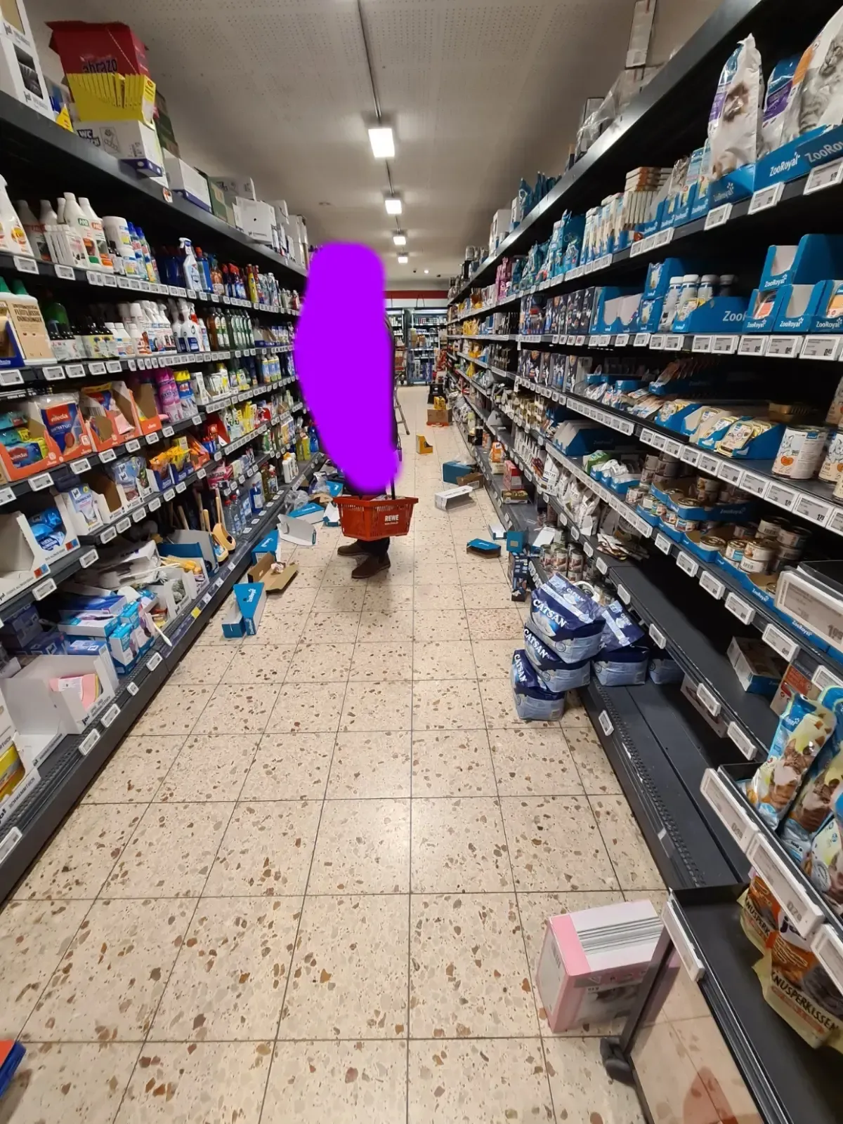 Einkaufsgang im REWE Duisburg‑Hamborn mit Kartons und verstreuter Ware am Boden.