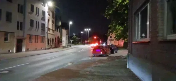 Beleuchtete Straße mit parkenden Autos in Duisburg bei Nacht