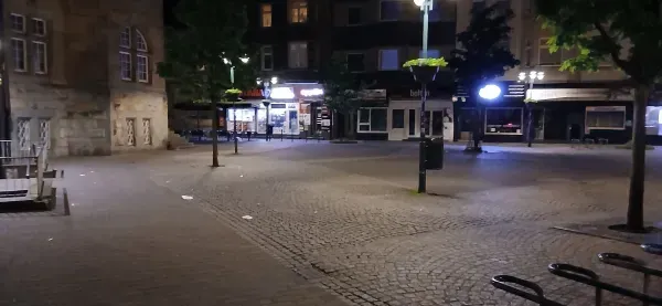 Vorplatz am Rathaus Hamborn mit beleuchteten Geschäften bei Nacht.