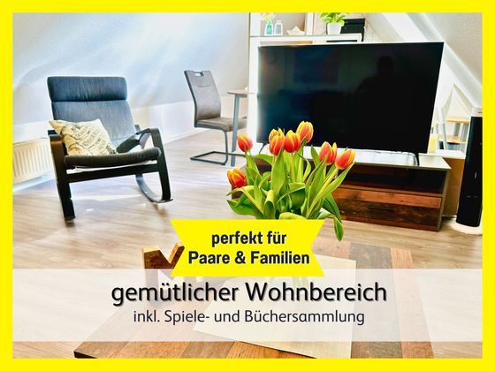 Wohnzimmer der Ferienwohnung Lütte Krabbe in Bensersiel mit Blick vom Schlafsofa auf den gemütlichen Schwingstuhl und den großen Smart-TV