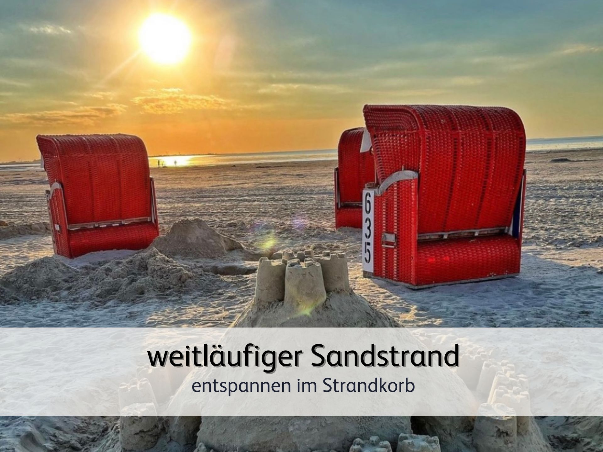 Drei rote Strandkörbe am Strand von Bensersiel bei Sonnenuntergang. Im Vordergrund steht keine kleine Sandburg