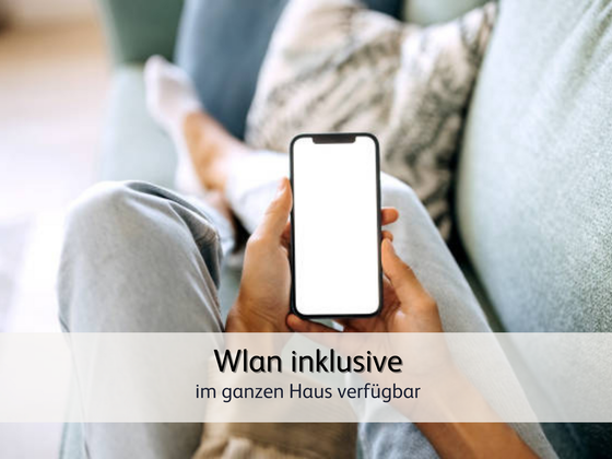 eine Person, die mit ihrem Handy das kostenlose Wlan der Ferienwohnung nutzt
