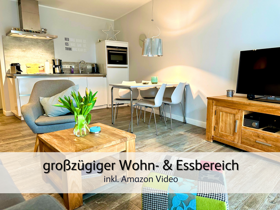 Wohnzimmer der FeWo StrandART in Norddeich mit Blick in den großzügigen  Wohnbereich samt Esstisch und Küchenzeile