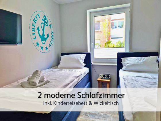 helles und modernes Zweitschlafzimmer der Ferienwohnung StrandART in Norddeich mit zwei gemütlichen Einzel-Boxspringbetten und Fernseher