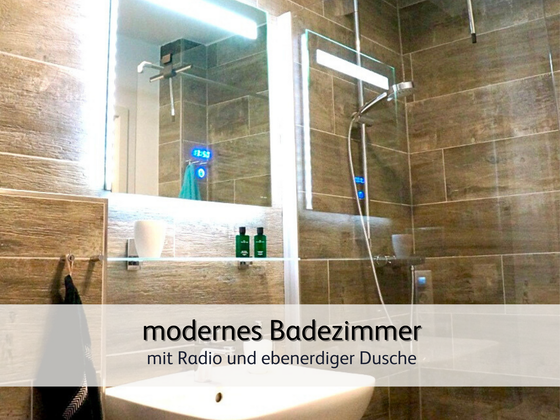 Badezimmer der Ferienwohnung StrandART in Norddeich in moderner Holzoptik samt Spiegel und bodengleicher Dusche