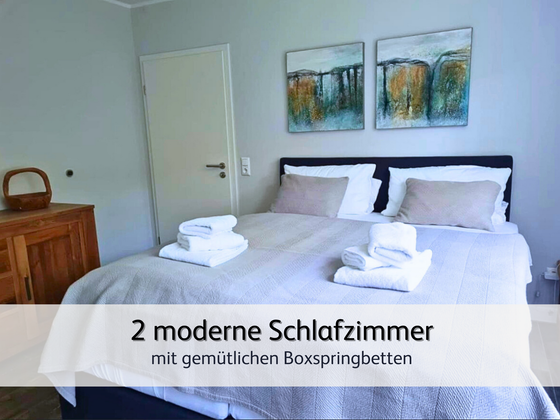 helles und modernes Hauptschlafzimmer der Ferienwohnung StrandART in Norddeich mit gemütlichem Doppel-Boxspringbett