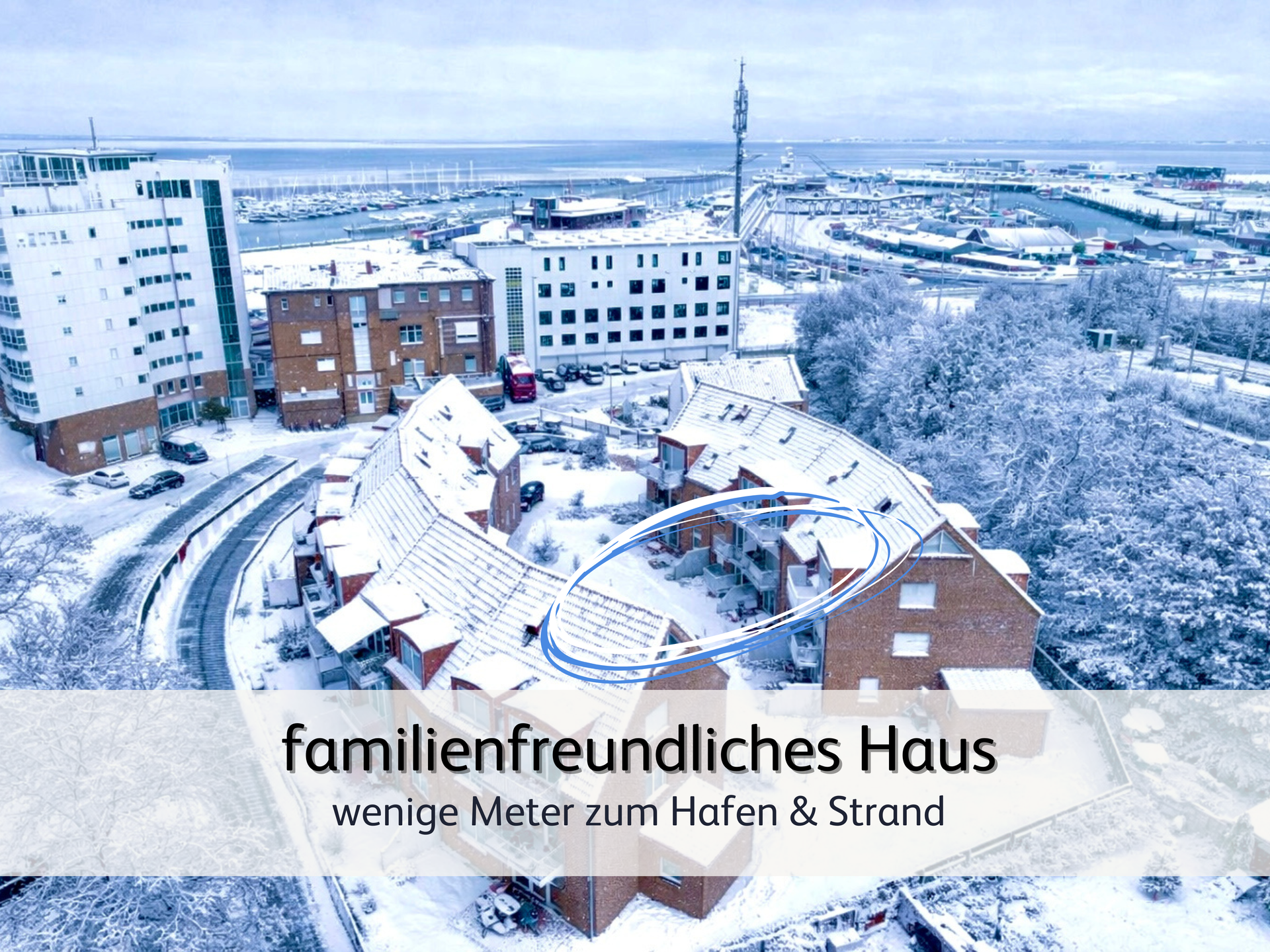 Luftaufnahme der winterlich verschneiten Ferienwohnung StrandART in Norddeich, im Hintergrund befindet sich nur wenige Meter entfernt der Hafen