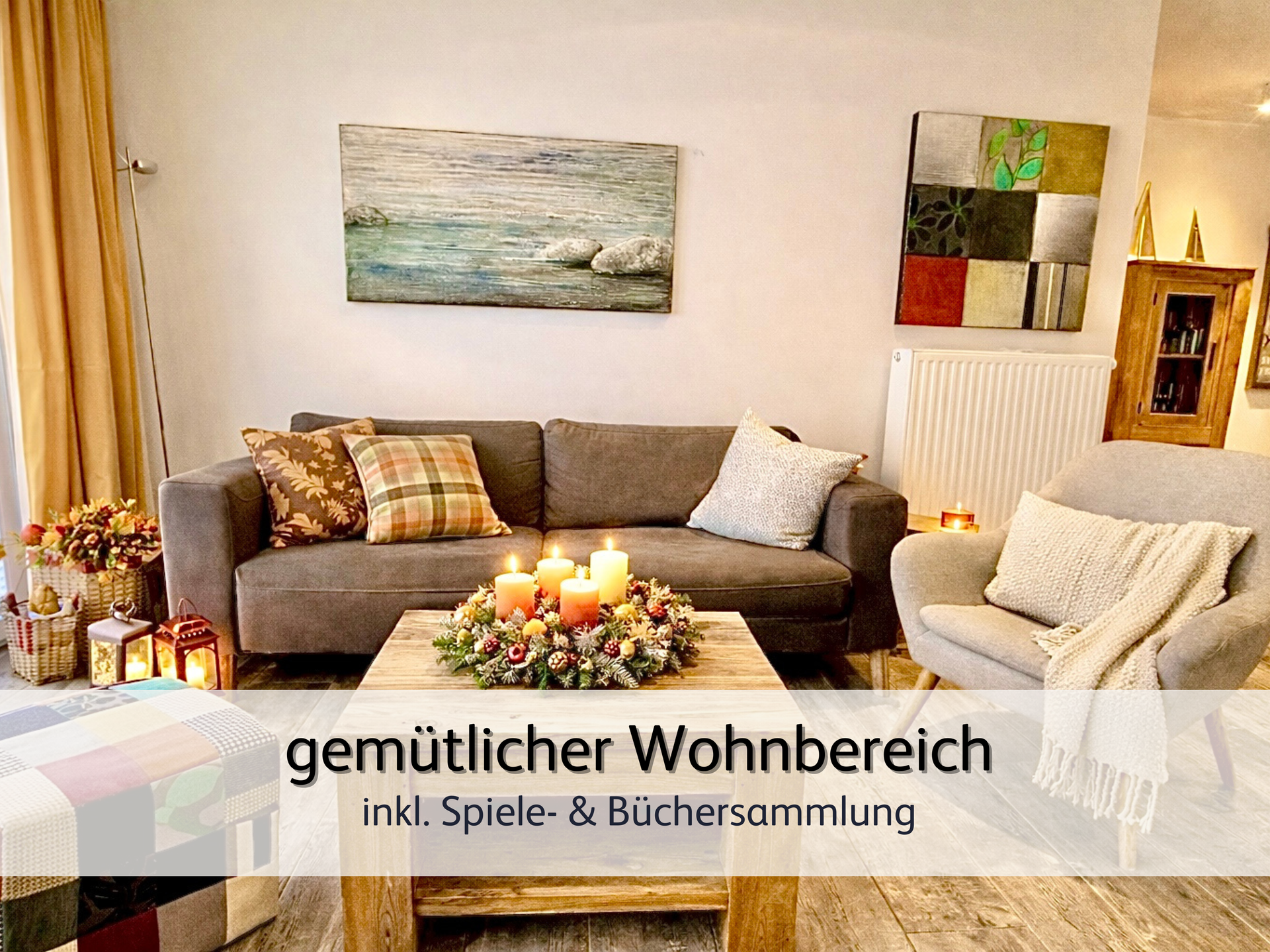 Wohnzimmer der FeWo StrandART in Norddeich mit Blick auf die gemütliche und herbstlich dekorierte Sofaecke. Auf dem Tisch vor dem Sofa ist ein herbstlicher Kranz mit 4 warm leuchtenden Kerzen.