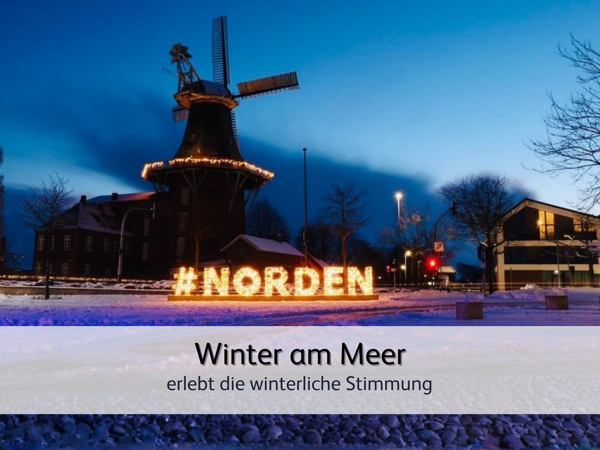 Die historische Windmühle von Norddeich bei Dämmerung. Im Vordergrund ist ein in warmer Farbe der Schriftzug 