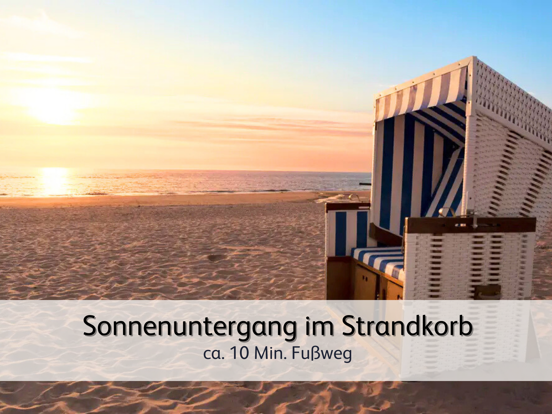 Ein Strandkorb am Strand. Im Hintergrund geht die Sonne in leuchtend warmen Farben über der Nordsee unter