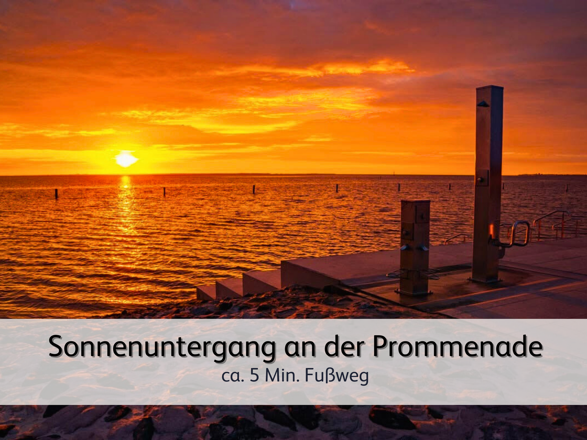Ein Sonnenuntergang an der modernen Strandpromenade von Norddeich färbt das Meer in warme Farben