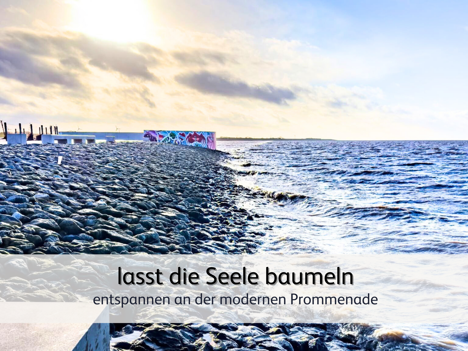 Blick auf die Strandpromenade von Norddeich bei Flut. Die Wellen schlagen gegen den Steinwall