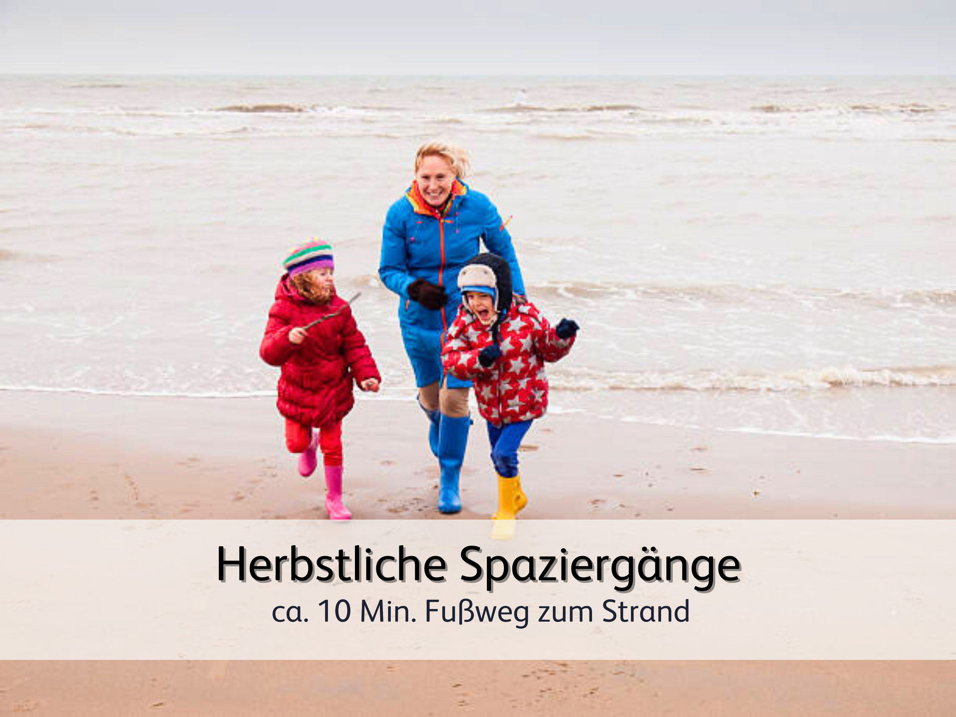 Eine Mutter, die den windigen Herbst am Strand mit ihren 2 Kindern beim Spielen genießt