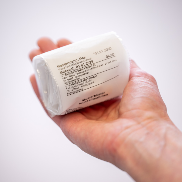 Blister-Service: Eine aufgewickelte Blister-Rolle mit Tabletten in der Hand liegend.