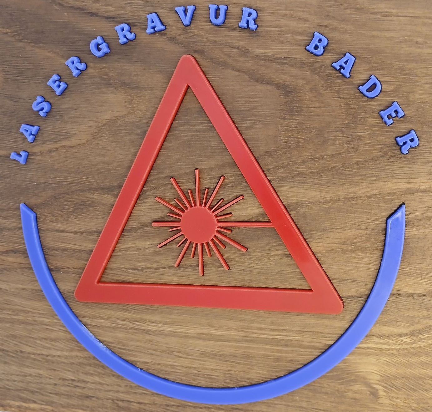 Logo Warnzeichen Laserstrahl mit Schriftzug Lasergravur Bader darüber und Halbkreis darunter