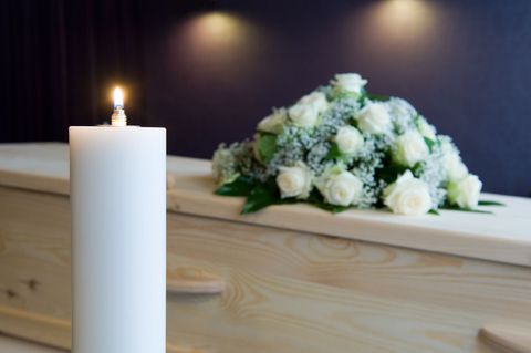 A candle and flowers on a coffin