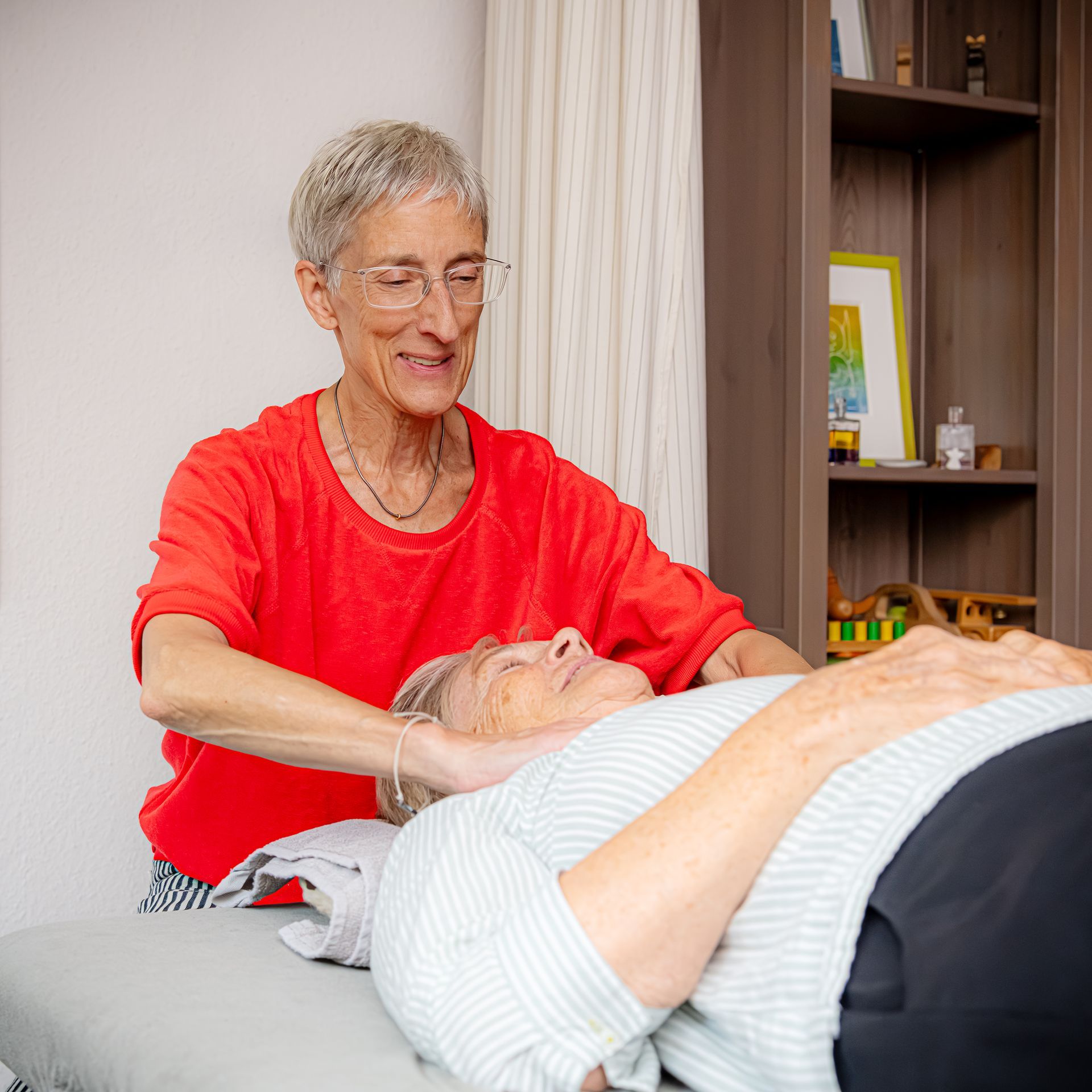 Physiotherapeutin stabilisiert das Knie einer Person mit einer speziellen Knieorthese während der Behandlung.