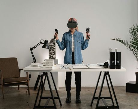 Junge Frau mit VR Brille hinter einem Schreibtisch