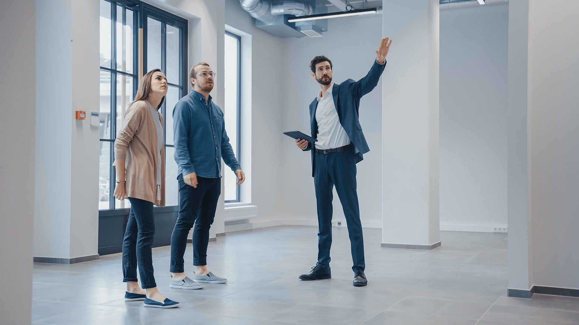 a realtor showing a large open room to a couple