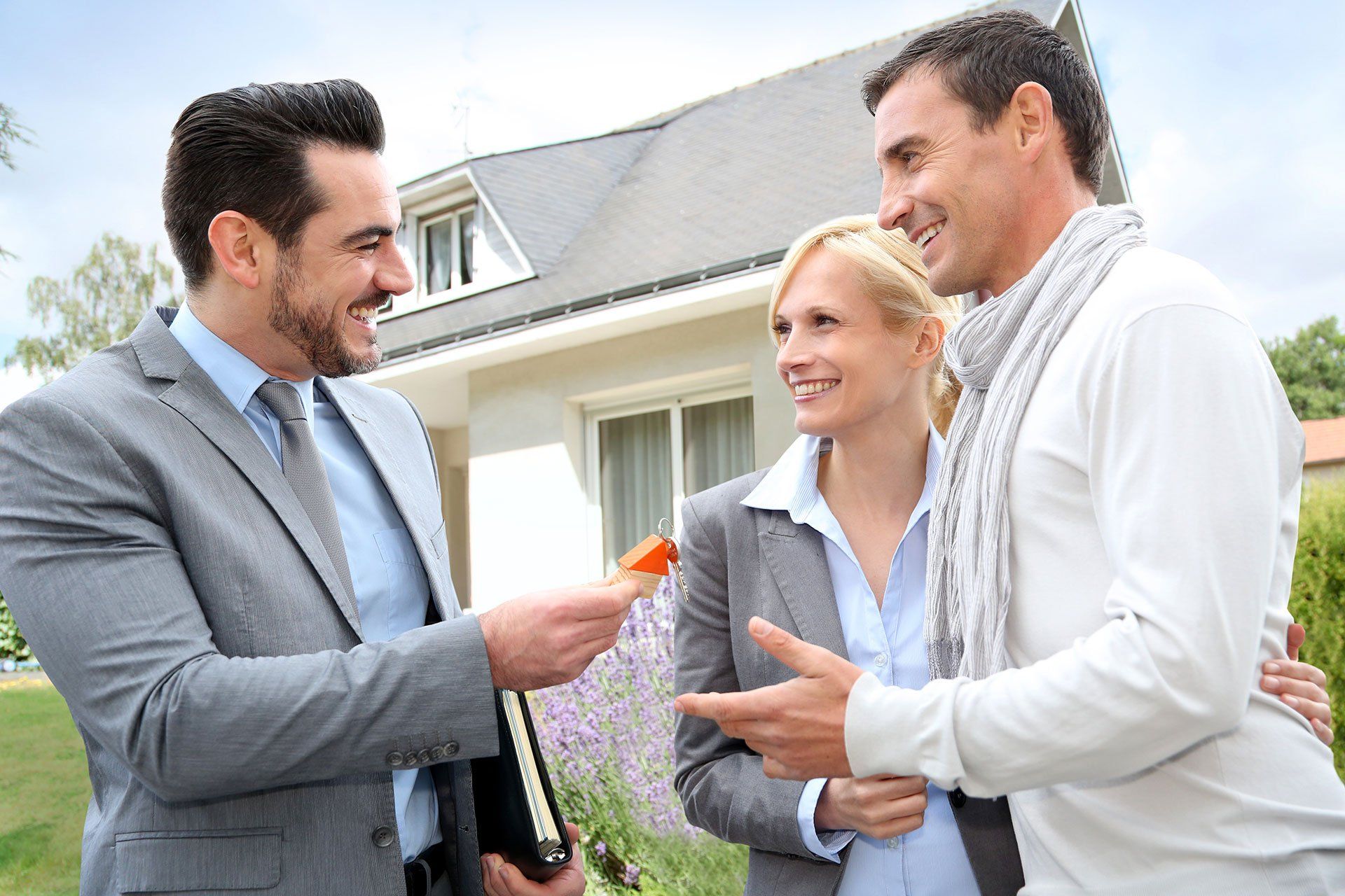 a man handing over the keys to a home to a couple