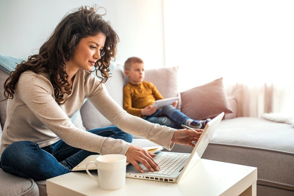 Mum working with son watching tv on the sofa