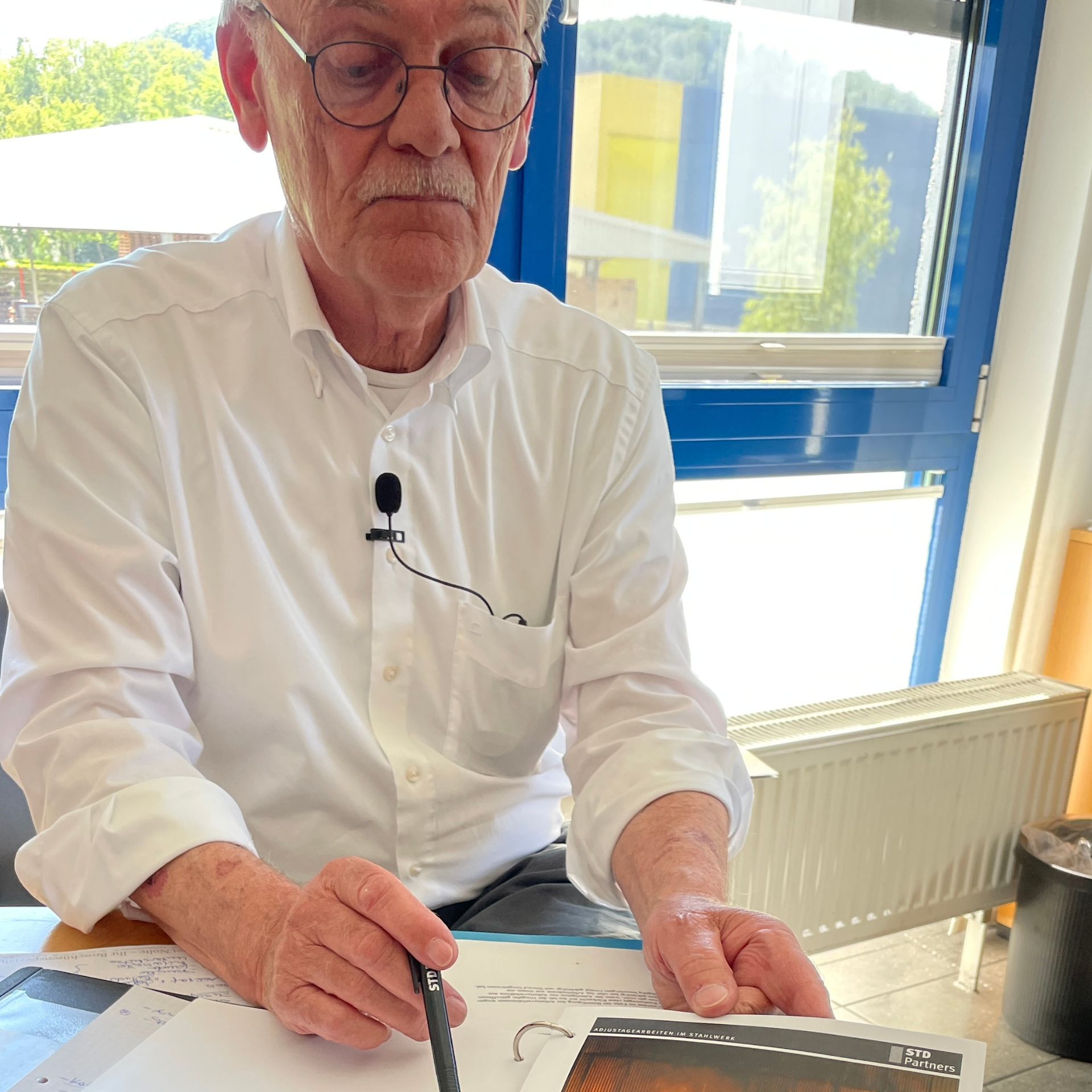 Unternehmer Uwe Paris zeigt auf Bilder aus alten Marketingbroschüren