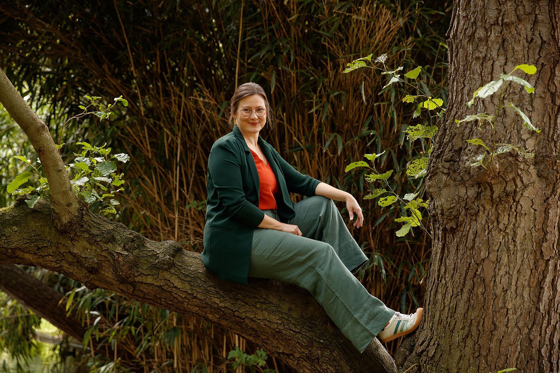 Claudia Corsten Coaching & Begleitung Porträt auf einem Baum sitzend, lächelnd