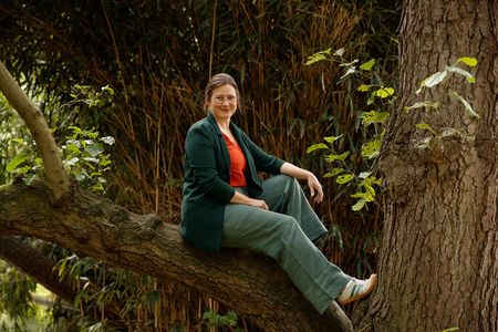 Claudia Corsten Coaching & Begleitung Porträt auf einem Baum sitzend, lächelnd