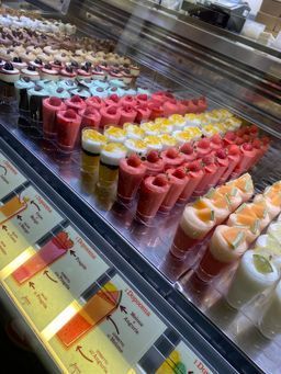 Verschiedene bunte Dessertbecher, in Reihen in einer Kühlvitrine angeordnet