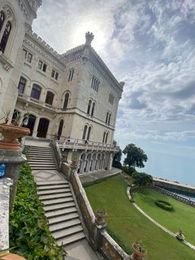 Prächtiges Steinhaus mit Treppe und gepflegtem Rasen, das unter einem bewölkten Himmel auf das Meer blickt