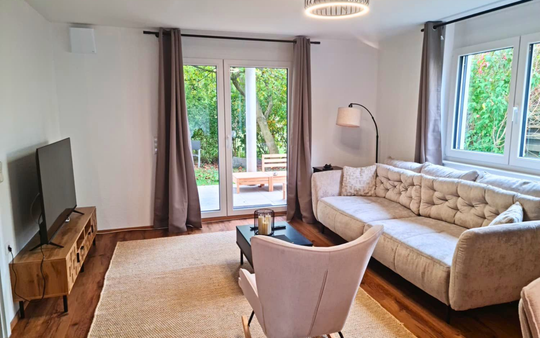 Heller Wohnbereich der 3-Zimmer-Ferienwohnung mit Sofa und Terrassenzugang in Unteruhldingen am Bodensee.