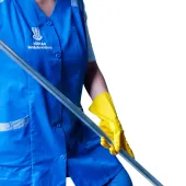 Eine Person in blauer Uniform und gelben Handschuhen hält einen Moppgriff.