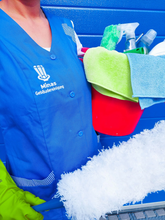 Person in blauer Uniform putzt Fenster mit einem grünen Schrubber und gelben Handschuhen.