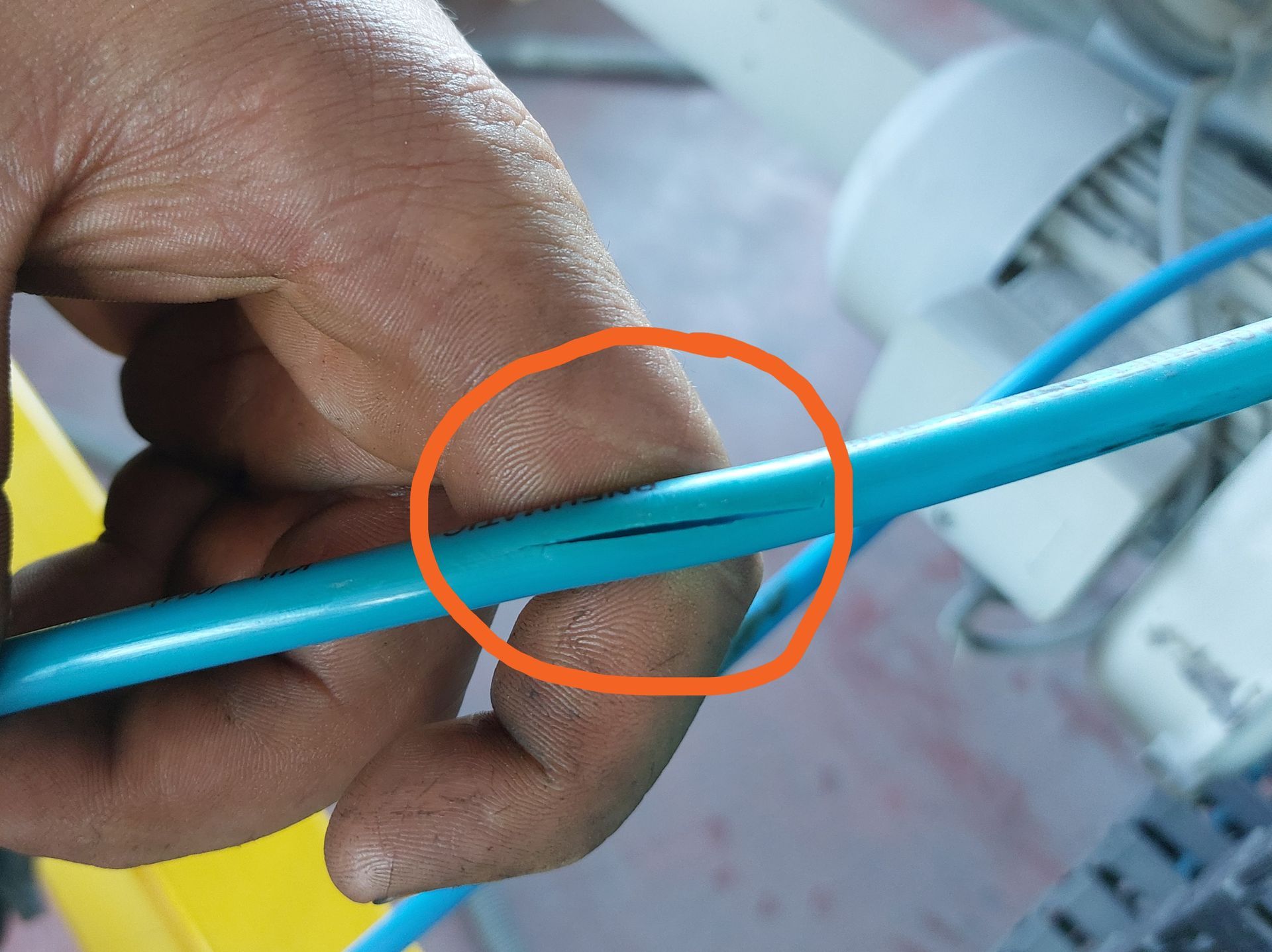Eine Hand hält einen Pneumatikschlauch mit einem Riss