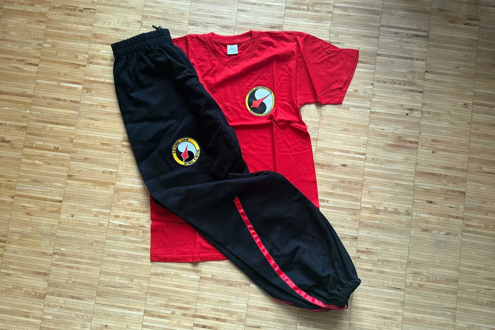 Schwarze Hose und ein rotes T-Shirt mit dem Leung Jan Wing Chun Logo.