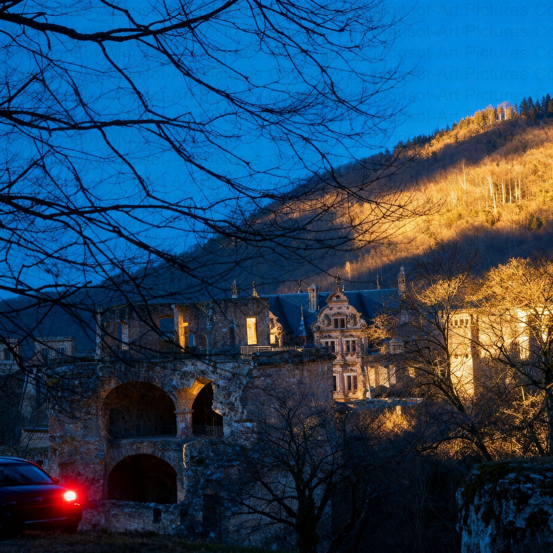 Eine alte Steinburg, im Abendrot beleuchtet, mit dem roten Rücklicht eines Autos. Im Hintergrund ein Berg.