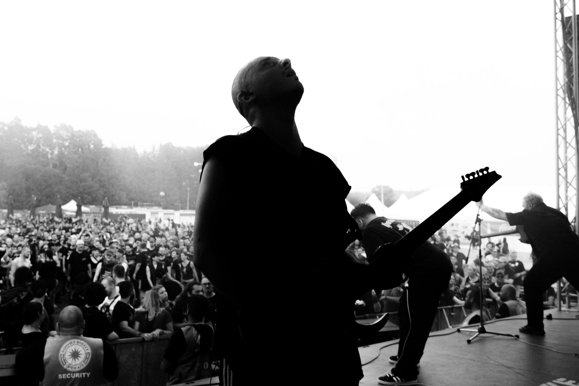 Mann mit E-Gitarre steht auf einer Bühne und schaut emotional und nachdenklich  in den Himmel