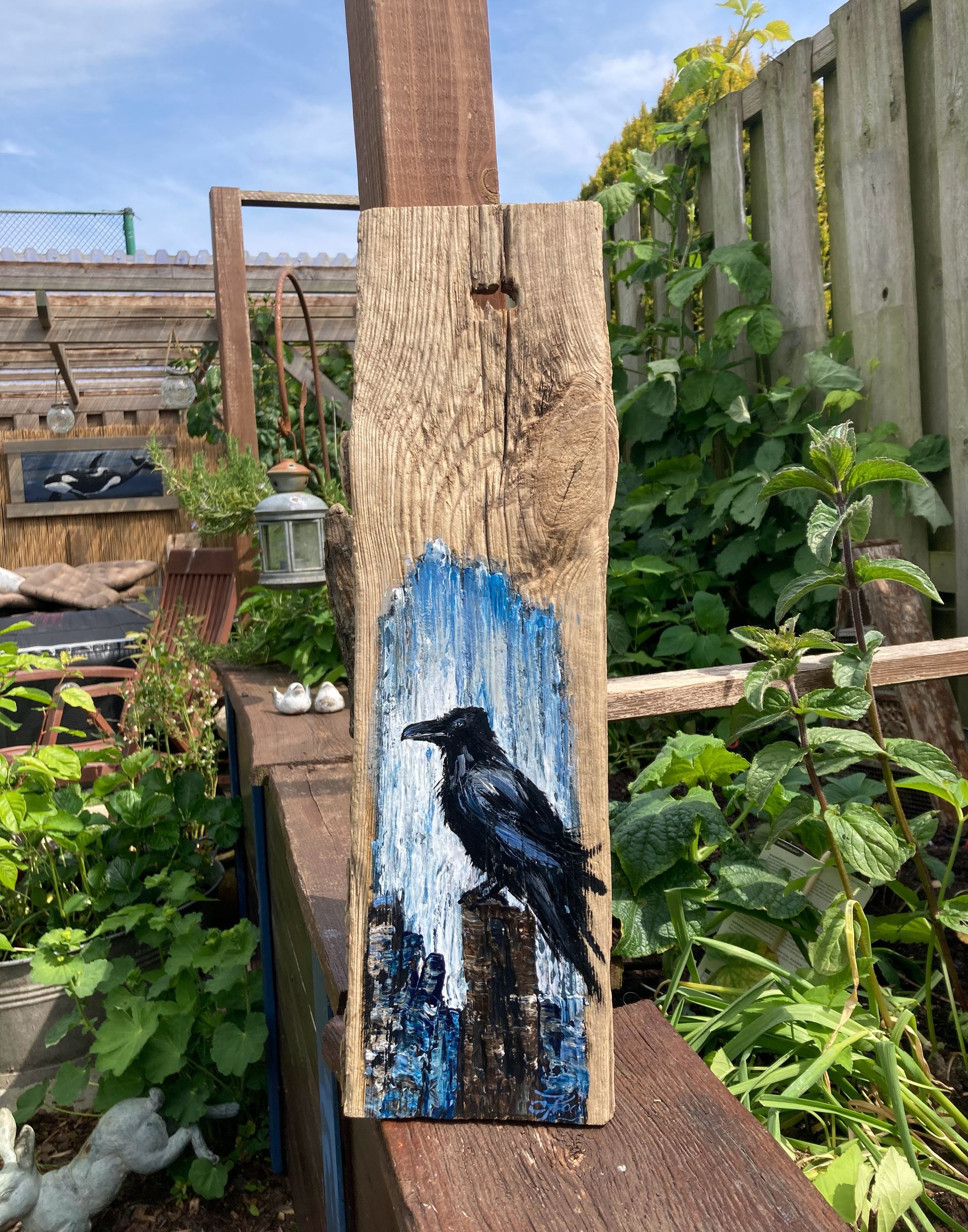 Eine Rabenkrähe auf einen sehr verwitterten Stück Treibholz gemalt.  Atelier am Deich