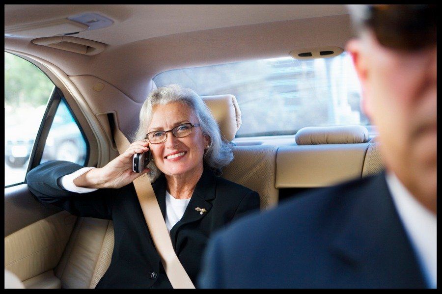 smiling woman on her phone in the back seat of a car