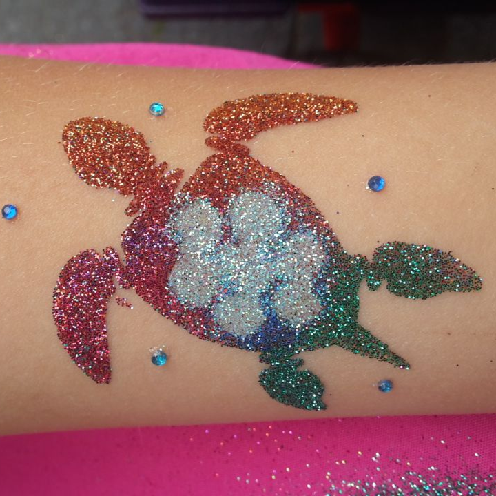 Temporäres Tattoo einer glitzernden Regenbogen-Meeresschildkröte auf dem Arm mit blauen Blasenverzierungen.