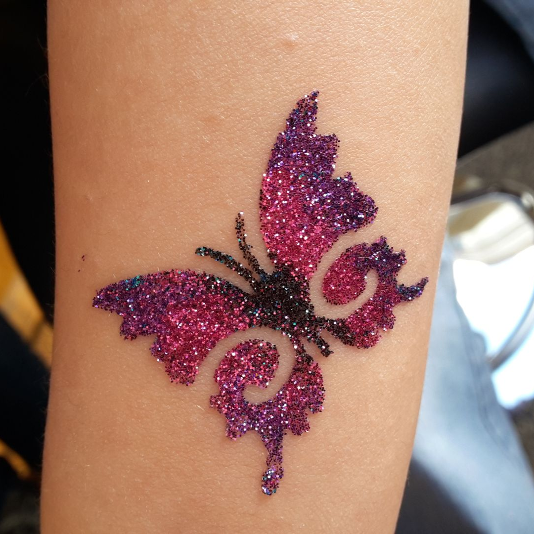 Glitzerndes, lila-pinkes Schmetterlings-Tattoo als temporäre Tätowierung auf dem Arm einer Person.