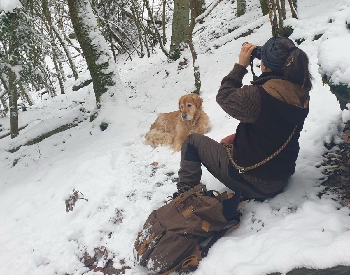 Frau mit Fernglas im Winterwald