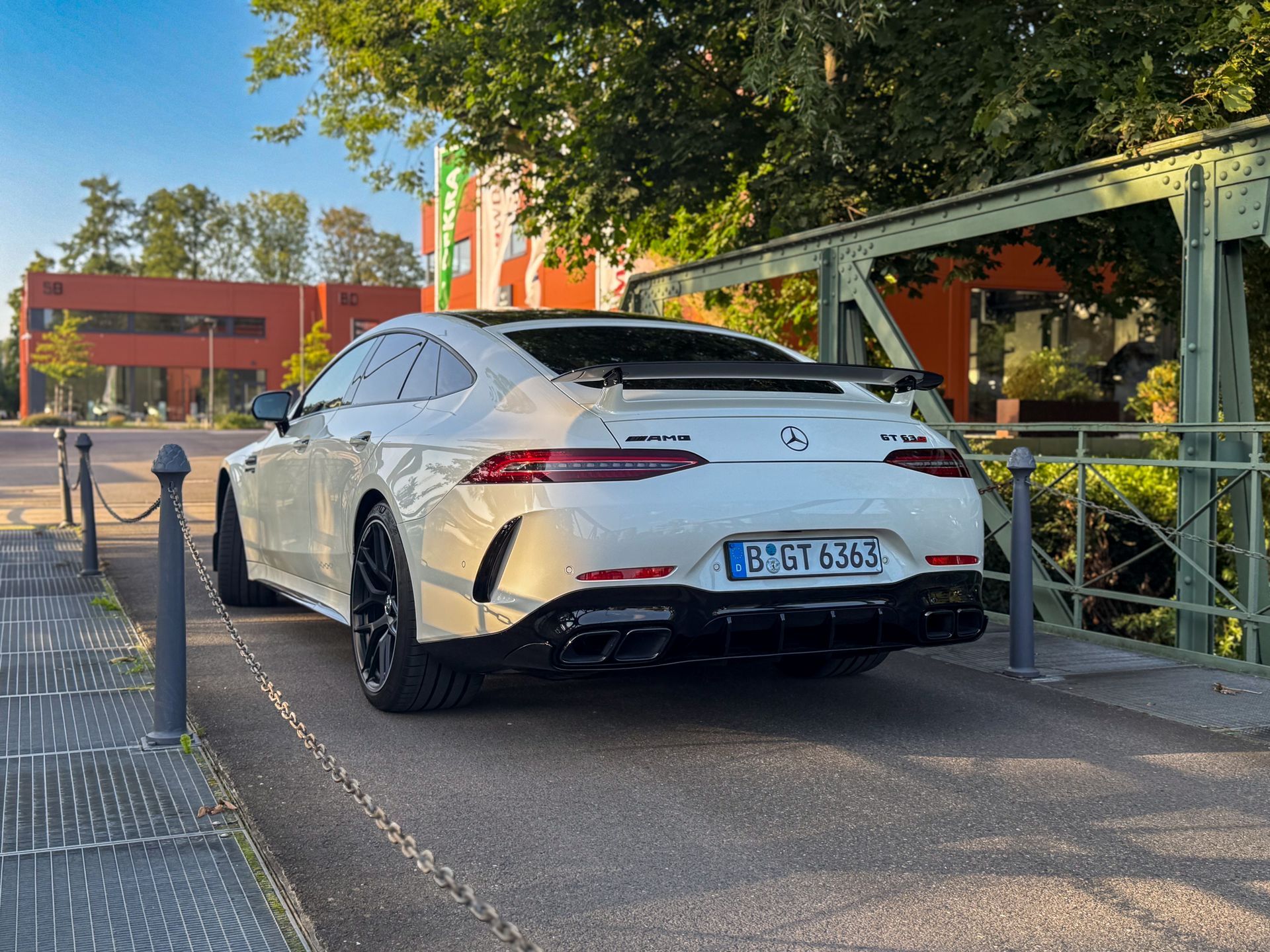 heck Ansicht von einem weißen AMG GT63s auf einer schmalen Brücke vor moderne Gebäuden AMG mieten Berlin