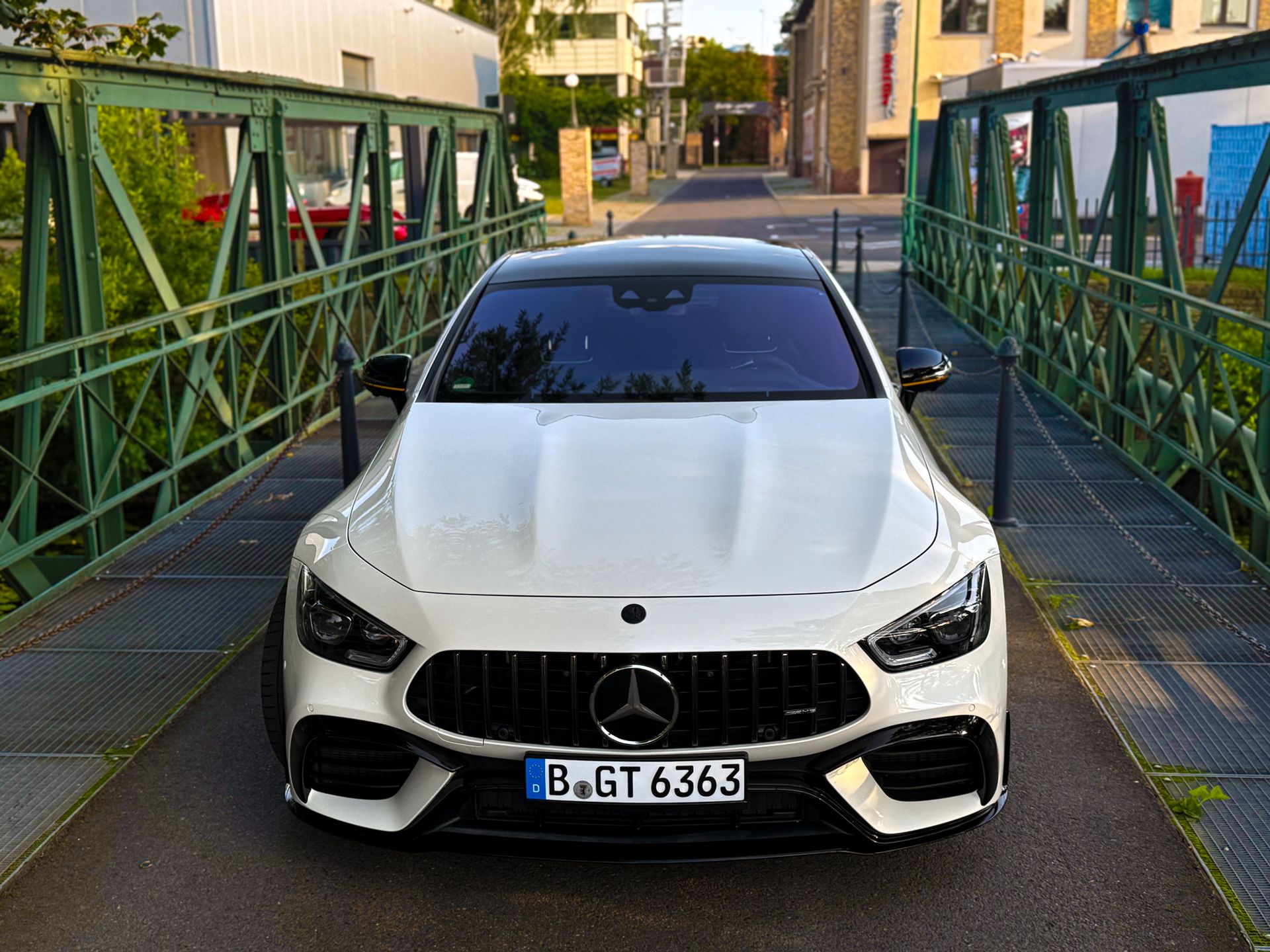 Frontalansicht des Mercedes-AMG GT63s auf schmaler Brücke mit urbanem Hintergrund bei Tageslicht Sportwagen mieten Berlin
