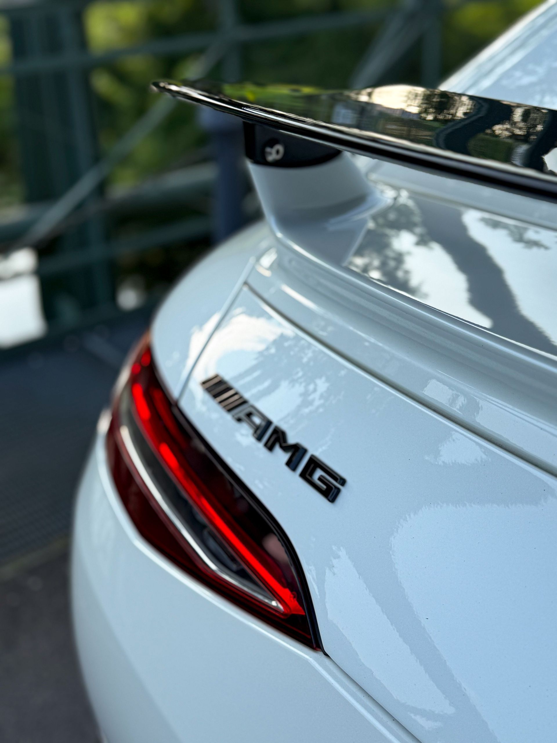Detailaufnahme des AMG-Heckspoilers und Rücklichts des weißen Mercedes GT63s mit Fokus auf das Logo