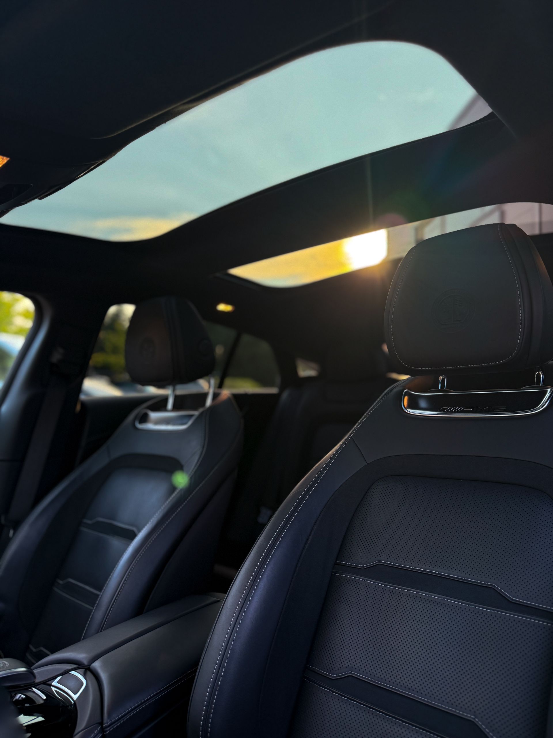 Innenraum des AMG GT63s mit Sicht auf die Vordersitze und beide geöffneten Panoramadächer, mit Sonnenlicht ins Fahrzeug