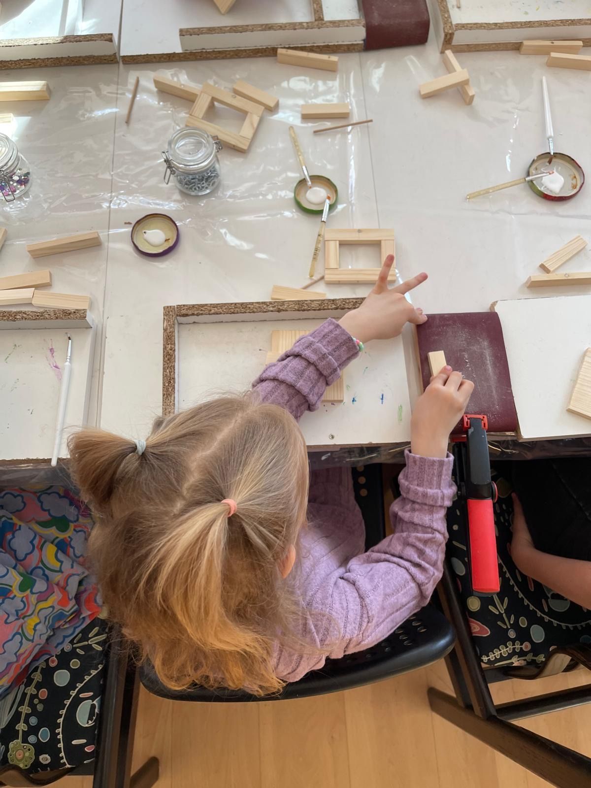 Kinder dekorieren ihren selbstgebauten Holzbausatz mit Farben und Accessoires