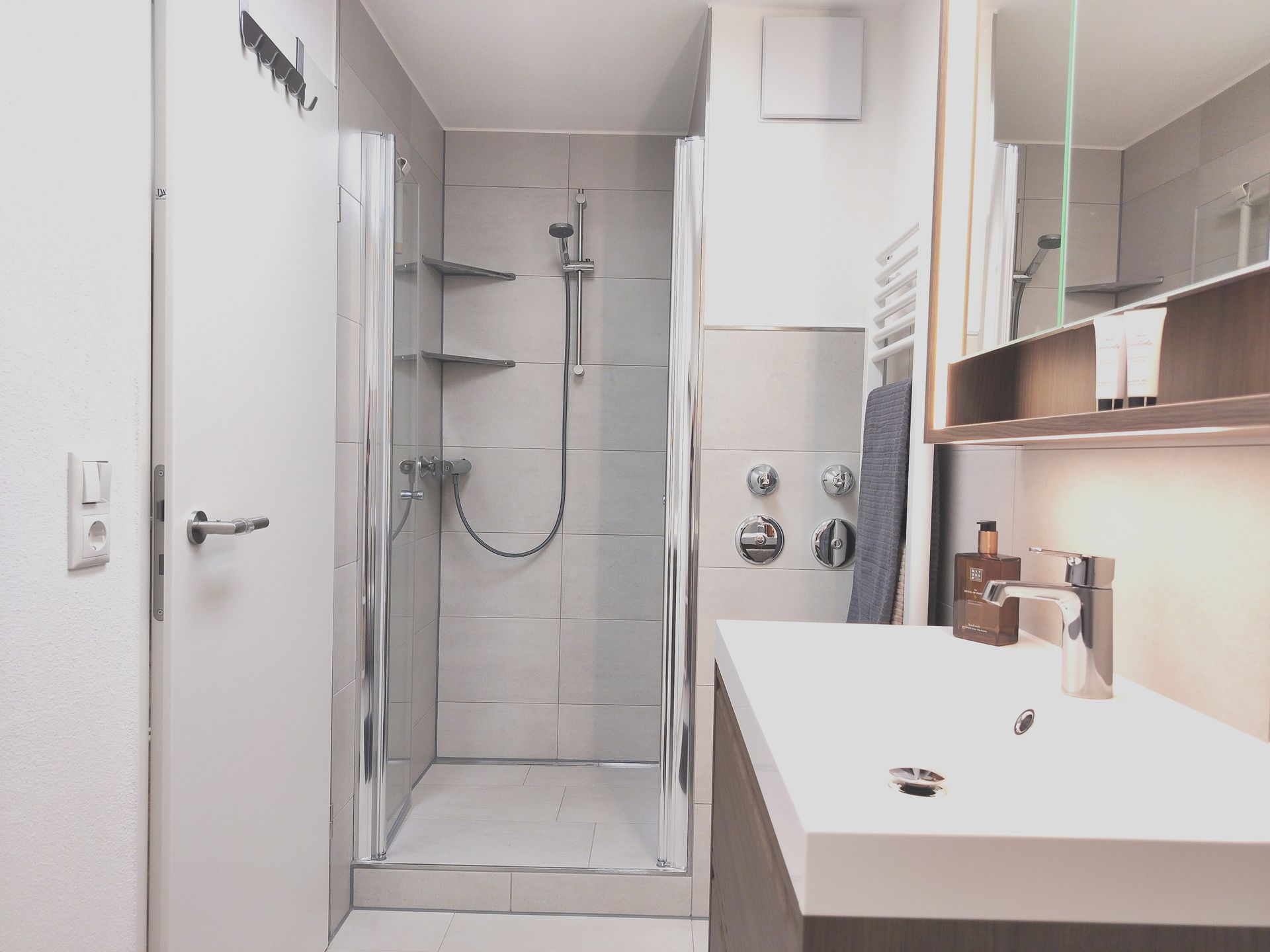 Modernes weißes Badezimmer mit ebenerdiger Dusche, Waschbecken und Spiegelschrank