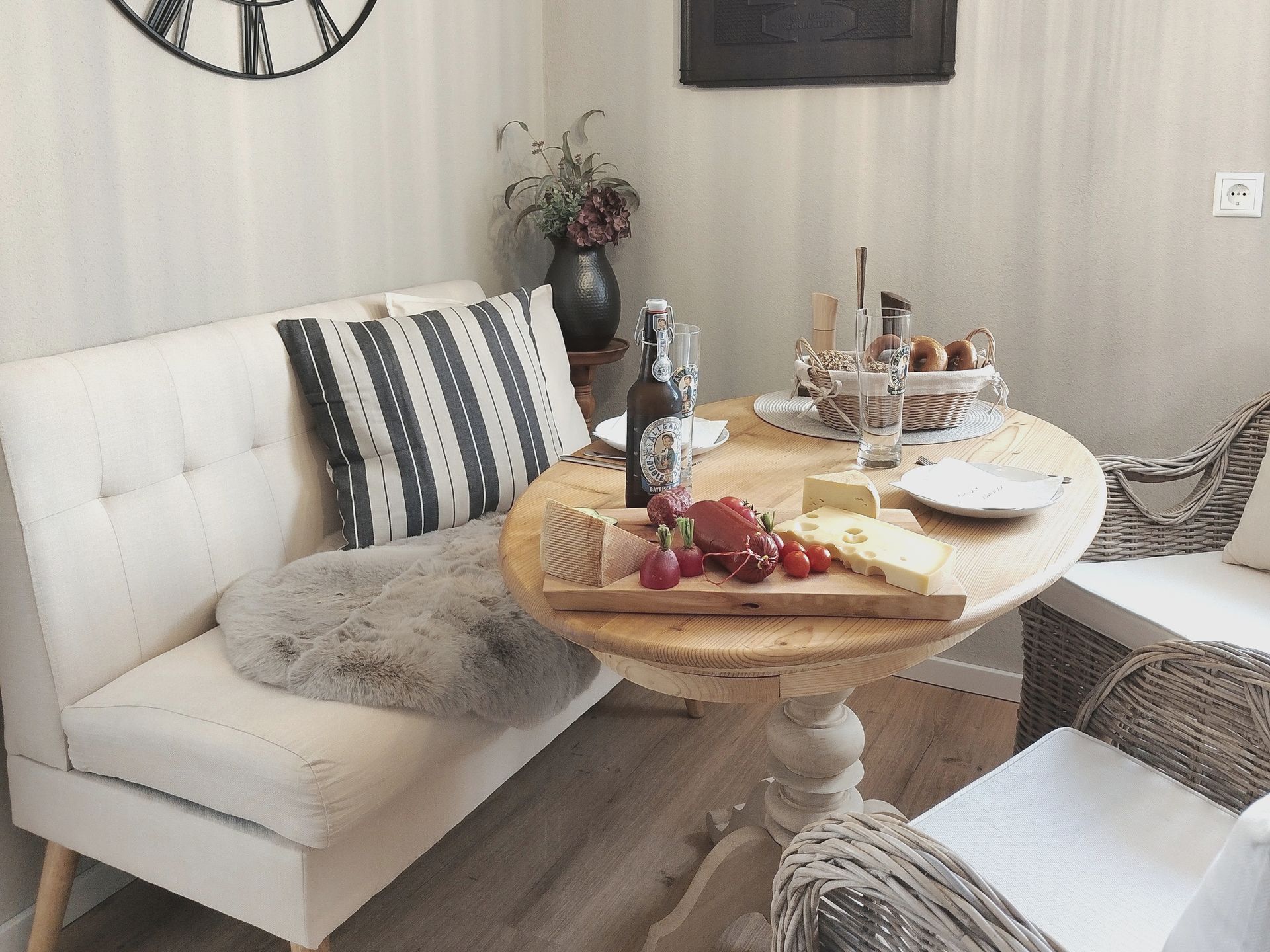 Helles Wohnzimmer mit weißem Sofa, rundem Couchtisch aus Holz und einem Tablett mit Getränken und Snacks.