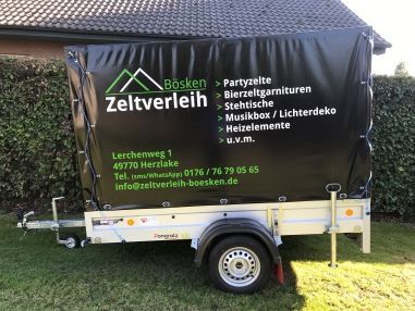 Ein schwarz abgedeckter Anhänger stand auf einem Rasen und warb mit dem Namen „Bösken Zeltverleih“ und den Kontaktdaten.